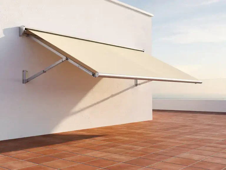 Moderne uittrekbare zonneluifel met gelede armen aan witte gevel boven terras met terracotta tegels in middagzon.