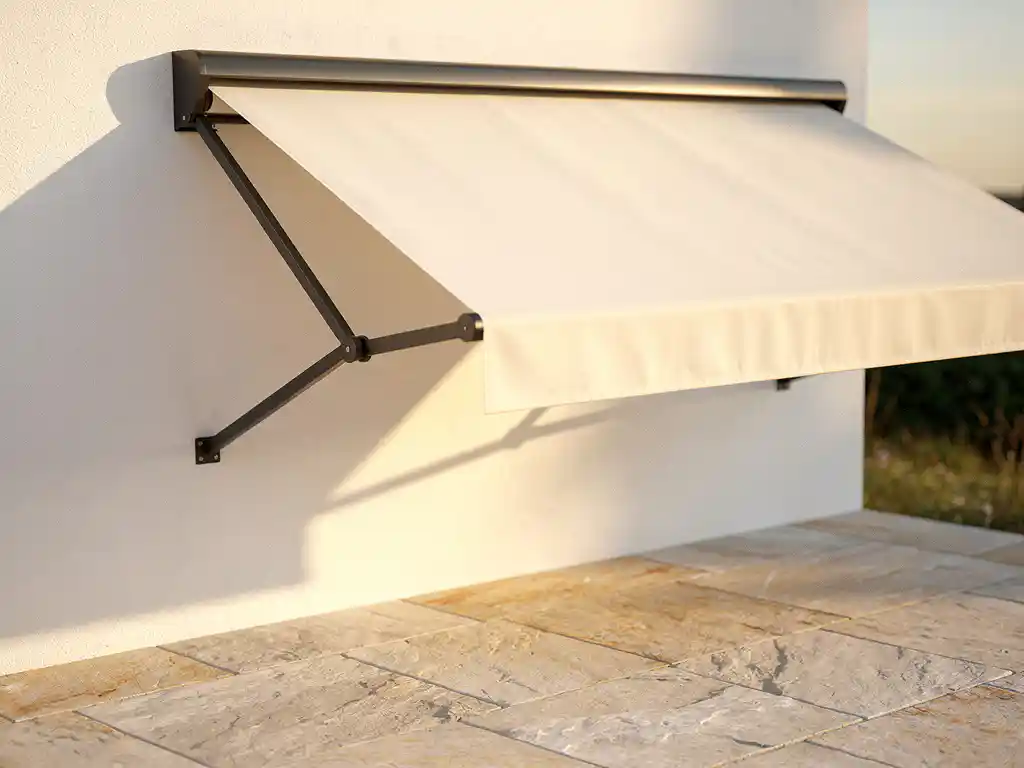 Uitschuifbare knikarmluifel in crème en antraciet op witte gevel, geometrische schaduw op zonnig stenen terras.